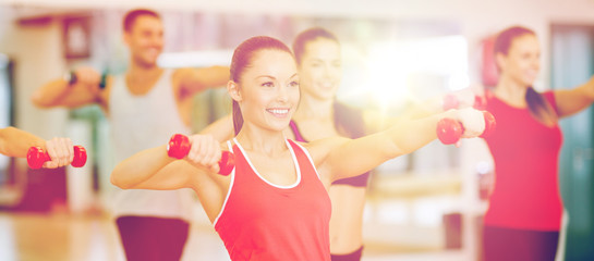 Poster - group of smiling people working out with dumbbells