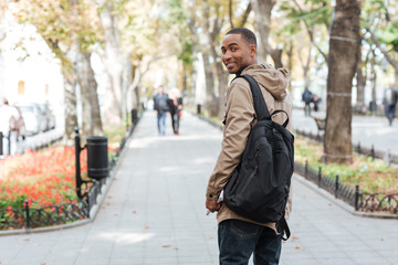 Poster - African happy man walking on the street while holding book