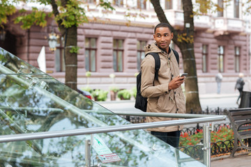 Poster - African man holding his phone in hands and looking aside