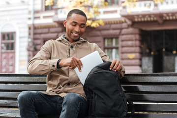 Poster - Young happy african man getting laptop from backpack