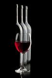 Fototapeta Panele - Elegant red wine glass and a wine bottles in black background.