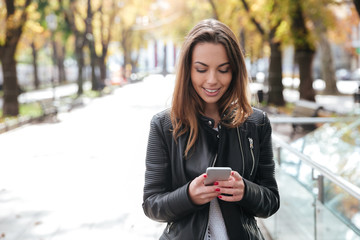 happy woman walking and using cell phone in the city