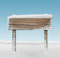 Wide wooden signpost with snow and blue sky