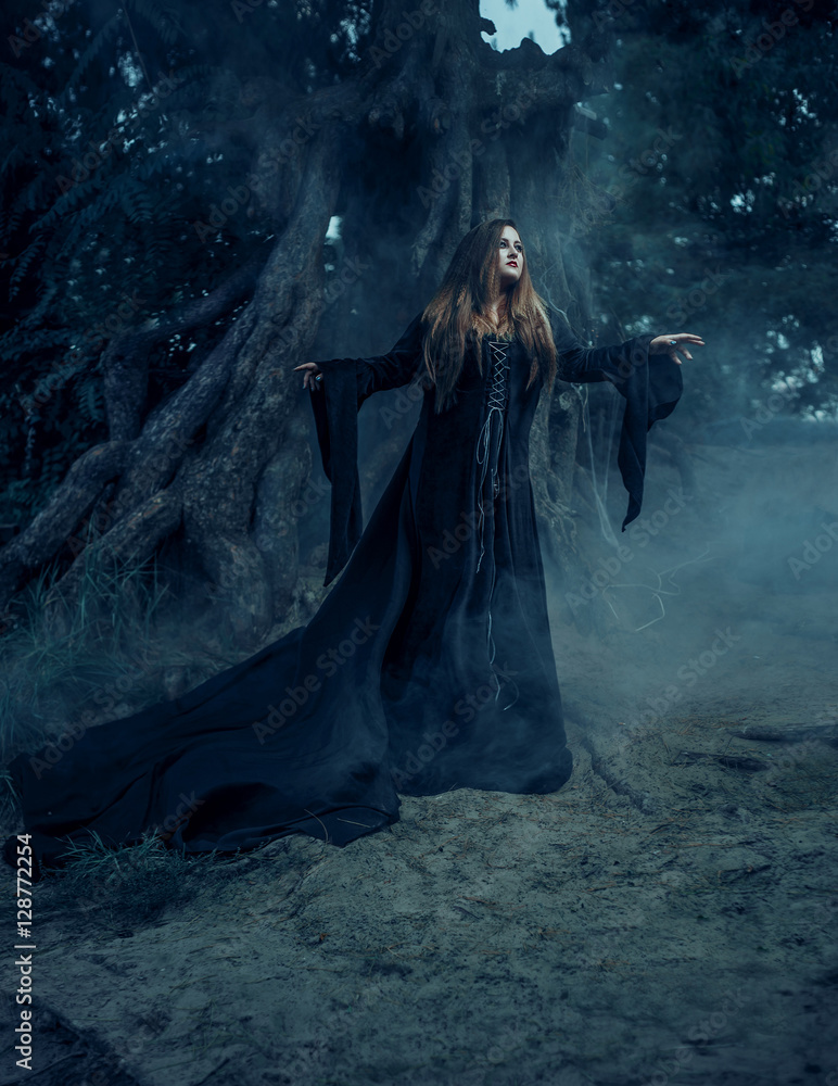 Dark witch casts a spell. In the background, mystical atmosphere. Photoshoot fantasy. Model big, beautiful woman. Unusual, gloomy, gothic decorations. - obrazy, fototapety, plakaty 