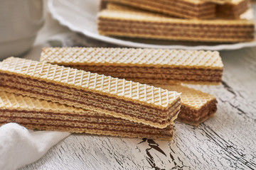 Wafer biscuits with chocolate cream on white rustic wooden background