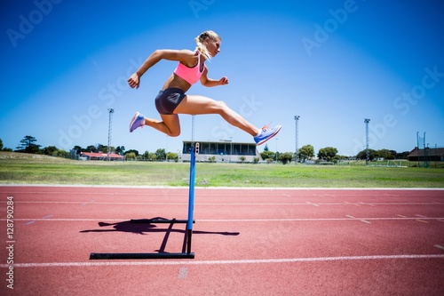 Cuadros en Lienzo Female athlete jumping above the hurdle