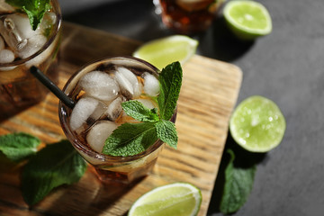 Canvas Print - Glasses of cocktail with ice on wooden cutting board closeup