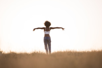 young black girl dances outdoors in a meadow