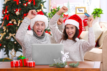 Wall Mural - Young couple shopping online with credit card at home for Christmas