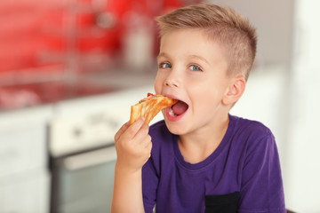 Cute boy eating pizza at home