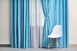 © Africa Studio - Chair and room window with white and blue curtains