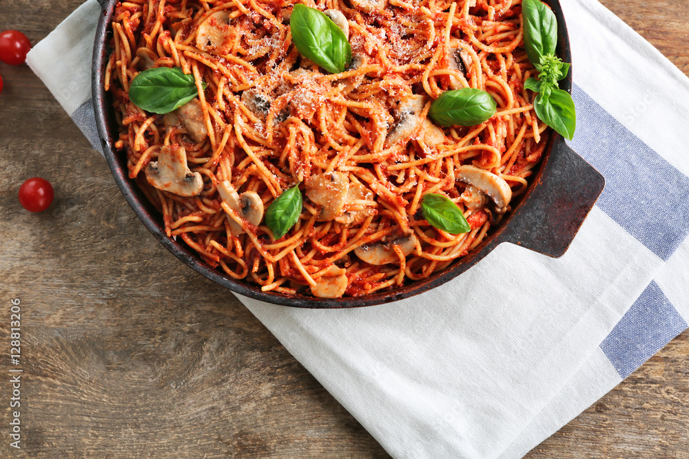 Pan with delicious pasta and napkin on wooden table, top view