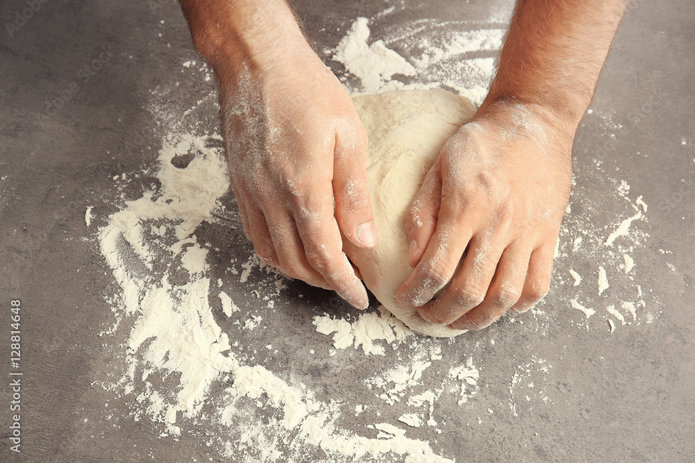 Male hands preparing dough for pizza on table closeup