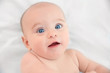 © Africa Studio - Cute baby lying on white bed sheet, close up view