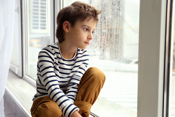 Cute little boy sitting on window sill