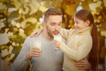 Wall Mural - Father and daughter with glasses of fresh milk outdoor