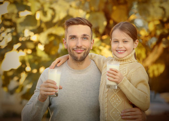 Wall Mural - Father and daughter with glasses of fresh milk outdoor