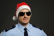© petrdlouhy - Portrait of smiling young policeman as santa claus on gray background