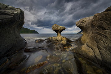 Unusual stone in Atlantic ocean coast. View on Kannesteinen and Kvalheimsvika. Over thousands of years, ocean waves have ground the rock to the special shape it has today. 2016 