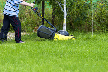 Young man gardener using lawn mower