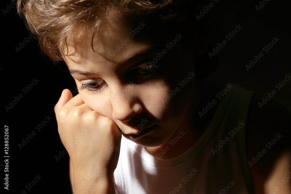 Cute little boy on black background, close up view