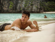 © theartofphoto - Half body shot of a handsome young man laying on a tropical beach in Phuket Island, Thailand, shirtless wearing boxer shorts, showing muscular fit body