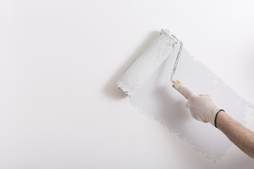 Close up of painter arm painting a wall in gray with paint roller