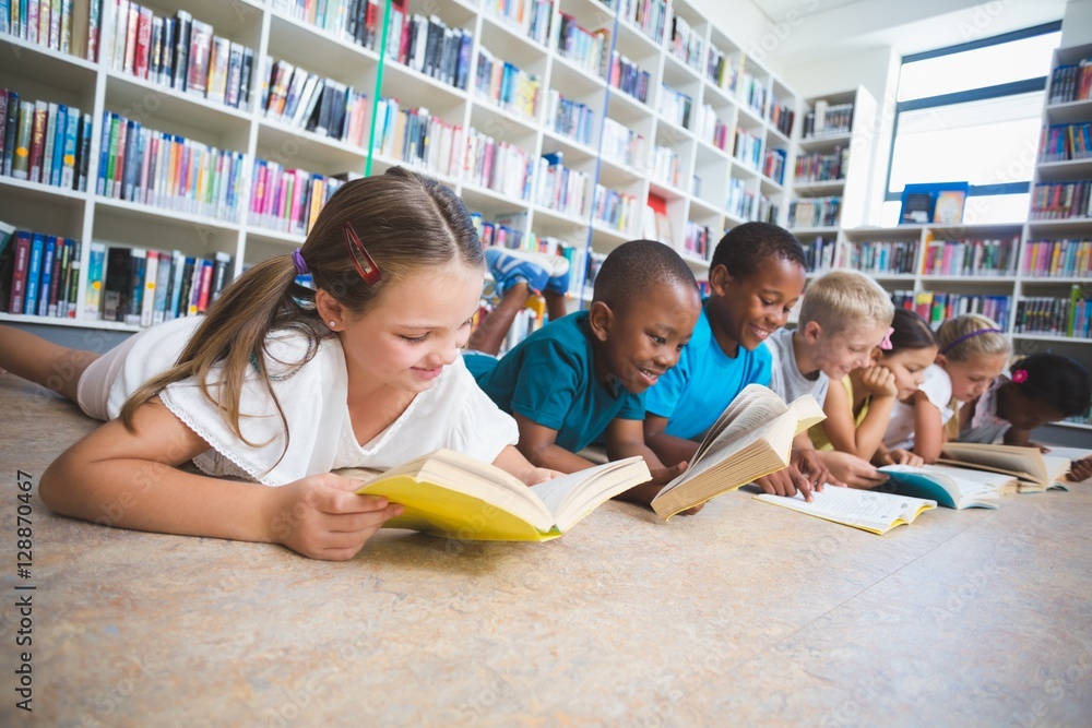 School kids lying on floor reading book in library Stock Photo | Adobe ...