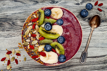 Wall Mural - Acai breakfast superfoods smoothies bowl with chia seeds, bee pollen, goji berry toppings and fruits. Overhead, top view, flat lay