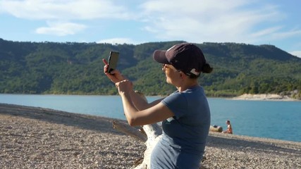 Wall Mural - Young woman taking a self-portrait with her smartphone in the mountains