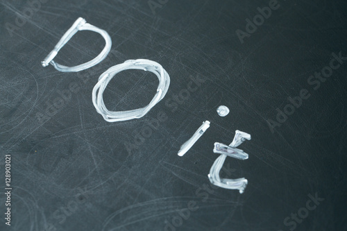 Juliste inscription do it drawn with chalk on a school blackboard dark