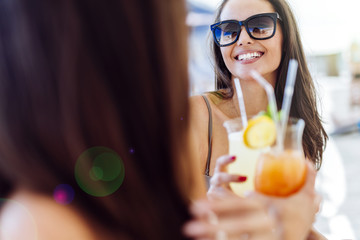 Wall Mural - Beautiful women on beach enjoying cocktails