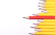 Pencils arranged horizontally in a jagged line with one standing out from the rest, with space for text