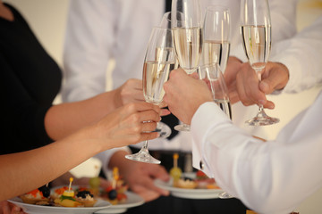 People clinking glasses at buffet catering party, close up view