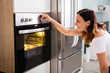 Woman Using Microwave Oven In Kitchen