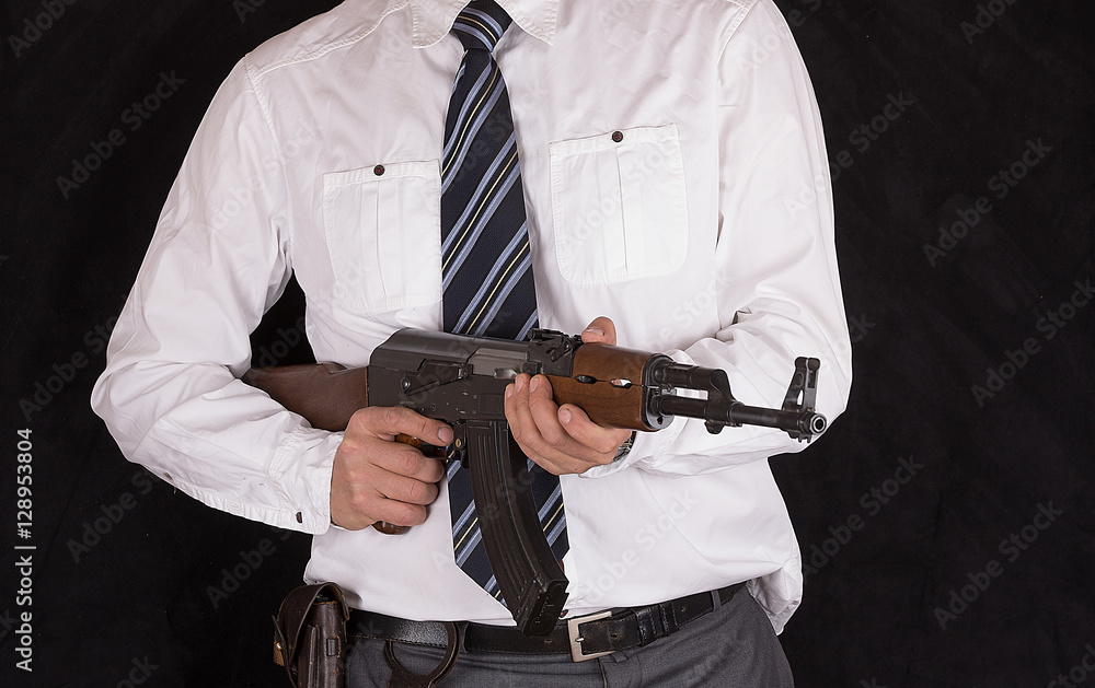 a man in a suit with a Kalashnikov assault rifle, a CIA agent, bodyguard
