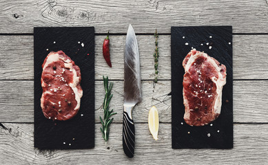 Wall Mural - Raw beef steaks on dark wooden table background, top view