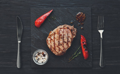 Wall Mural - Grilled beef steak on dark wooden table background, top view