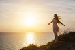 Beautiful free happy woman in white dress enjoying the golden sunshine glow of sunset with arms outspread, serenity in nature. Enjoyment, wind in blond hair