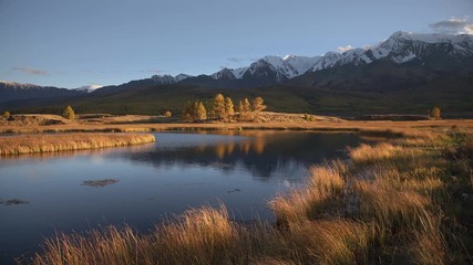 Wall Mural - Breathtaking View Of The Still Water River Reflecting Sky Surrounded By Scenery With Yellow Grass And Range Of Siberian Mountains