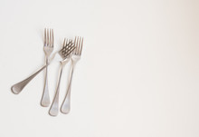 Food Background - High Angle View Of Four Forks Scattered On White Table With Copy Space To Right
