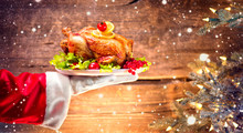 Christmas Holiday Dinner. Santa's Hand Holding Roasted Chicken Over Wooden Background