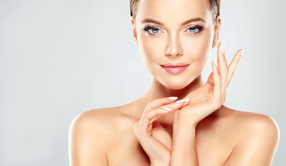 Wall Mural - beautiful young woman with clean fresh skin touch own face . facial treatment . cosmetology , beauty