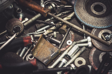 Auto mechanic metal parts and tools on a table. Close up view of finishing equipment, drills, bits, screws, bolts.