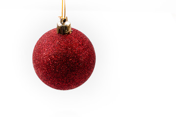 Red Christmas ball hanging in midair against a white background