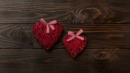 Concept of Valentine's Day. Wicker hearts on dark wooden backgro