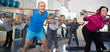 © caftor - elderly exercise with gymnastic sticks in modern gym