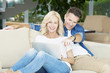 © sepy - Portrait of middle aged couple sitting with a laptop at home. Beautiful blond woman using laptop while handsome man sitting next to her and enjoy surfing on internet.