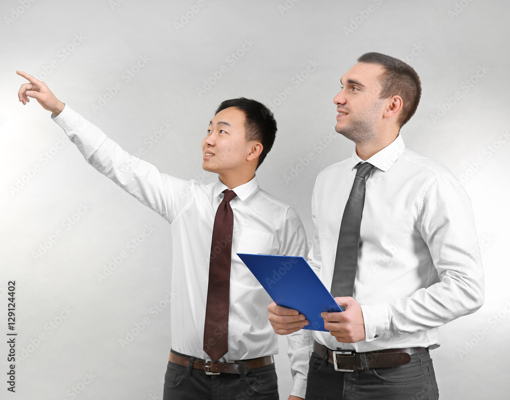 Handsome men discussing something on light background