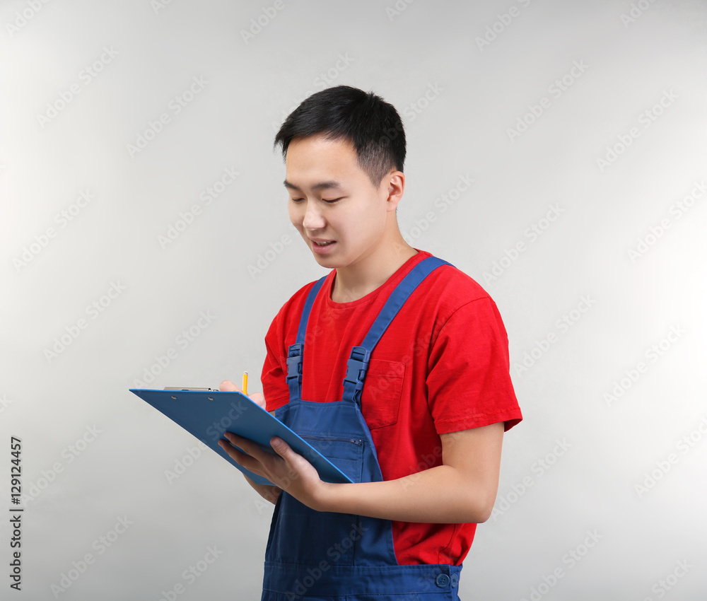 Asian warehouse worker with clipboard on light background